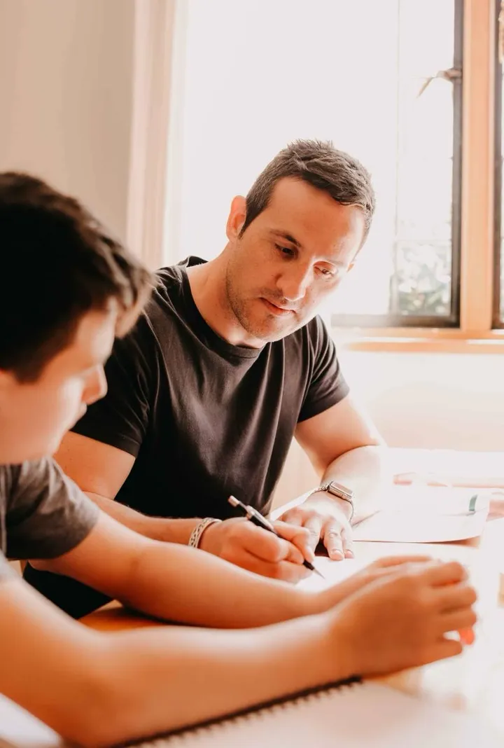 Ben Walker helping a student with written work at a table